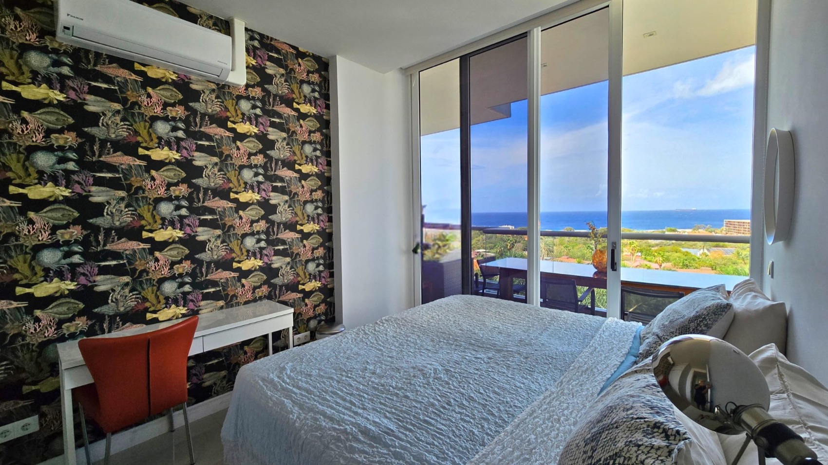 Second bedroom at Cur Azul with a striking sea-life feature wall, double bed, desk and floor-to-ceiling doors onto a sea-view balcony