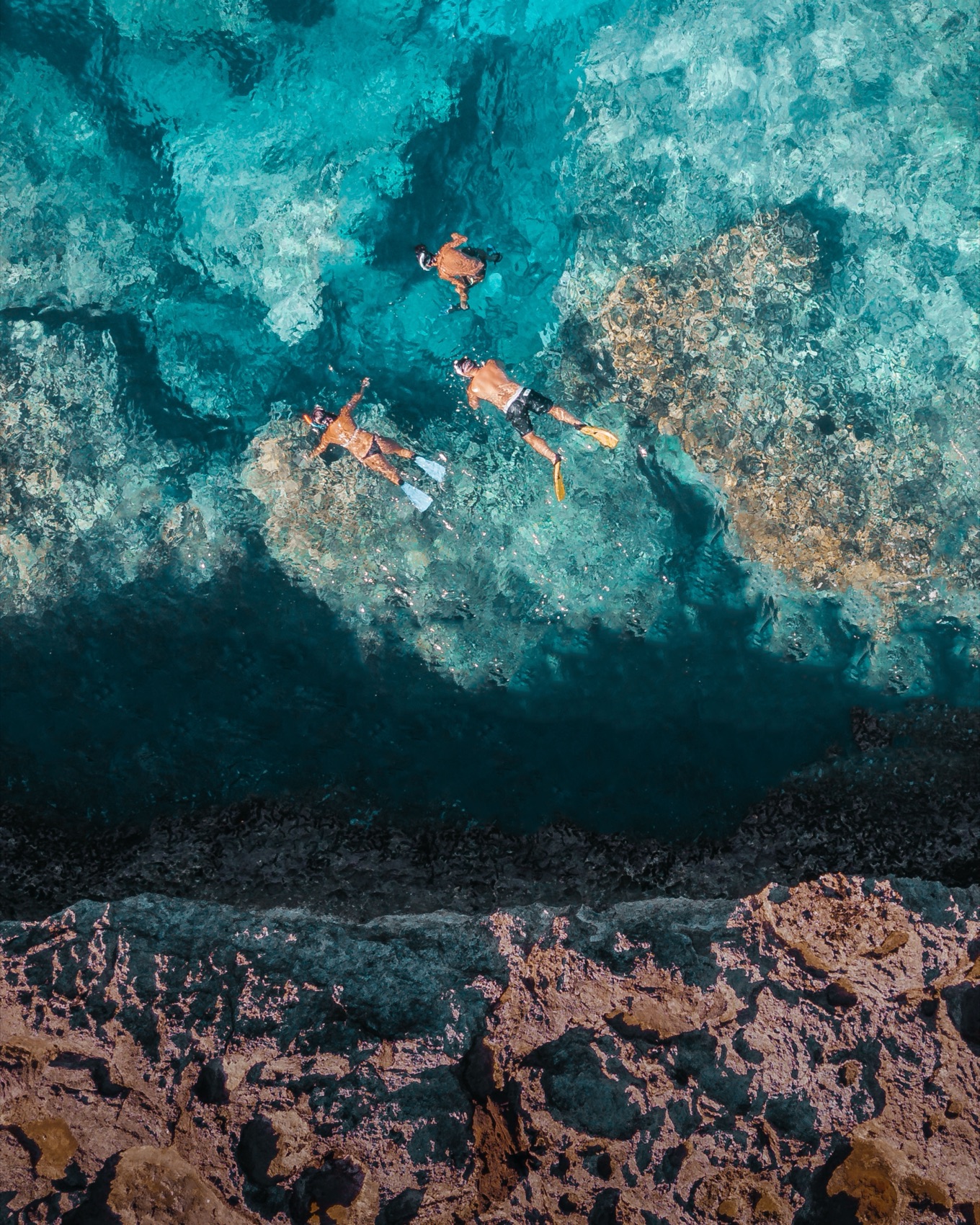 Aerial view of snorkellers gliding over a clear coral reef off the Curaçao coast