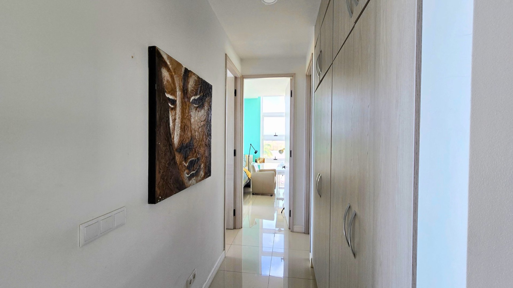 Bright entrance hallway at Cur Azul with art and fitted wardrobes leading to the living space