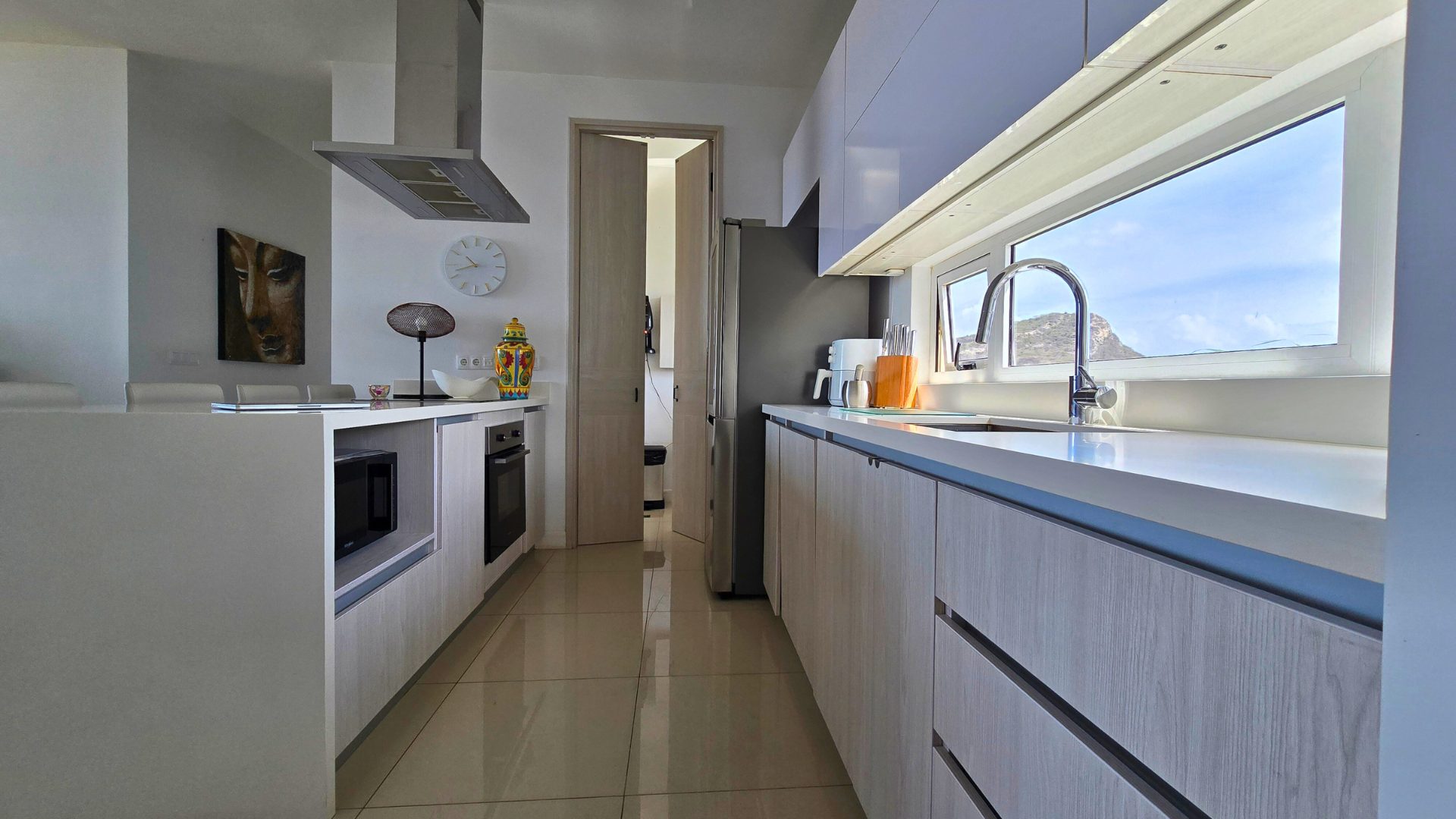 Galley section of the Cur Azul kitchen with light wood cabinetry, oven and a window framing the hills