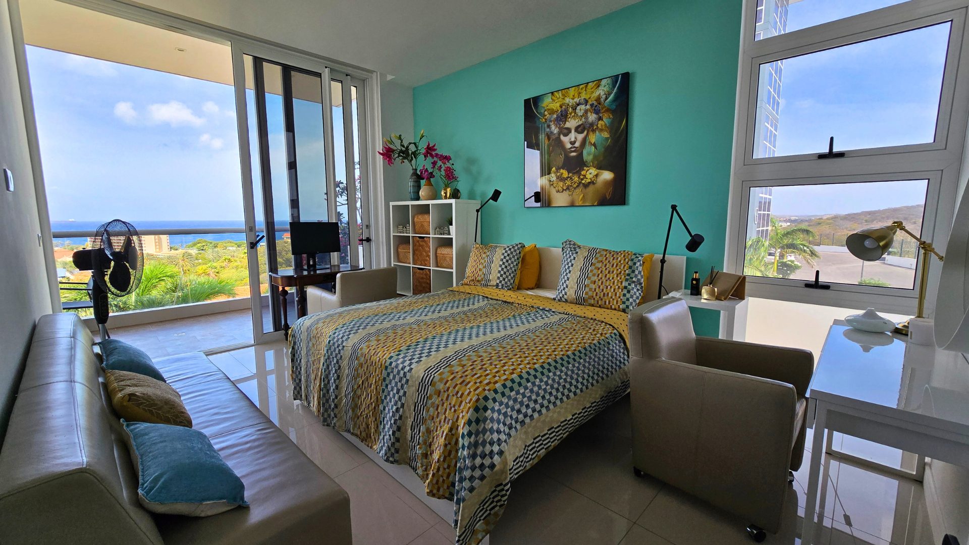 Master bedroom at Cur Azul with king bed, teal accent wall and floor-to-ceiling windows opening to the sea-view balcony